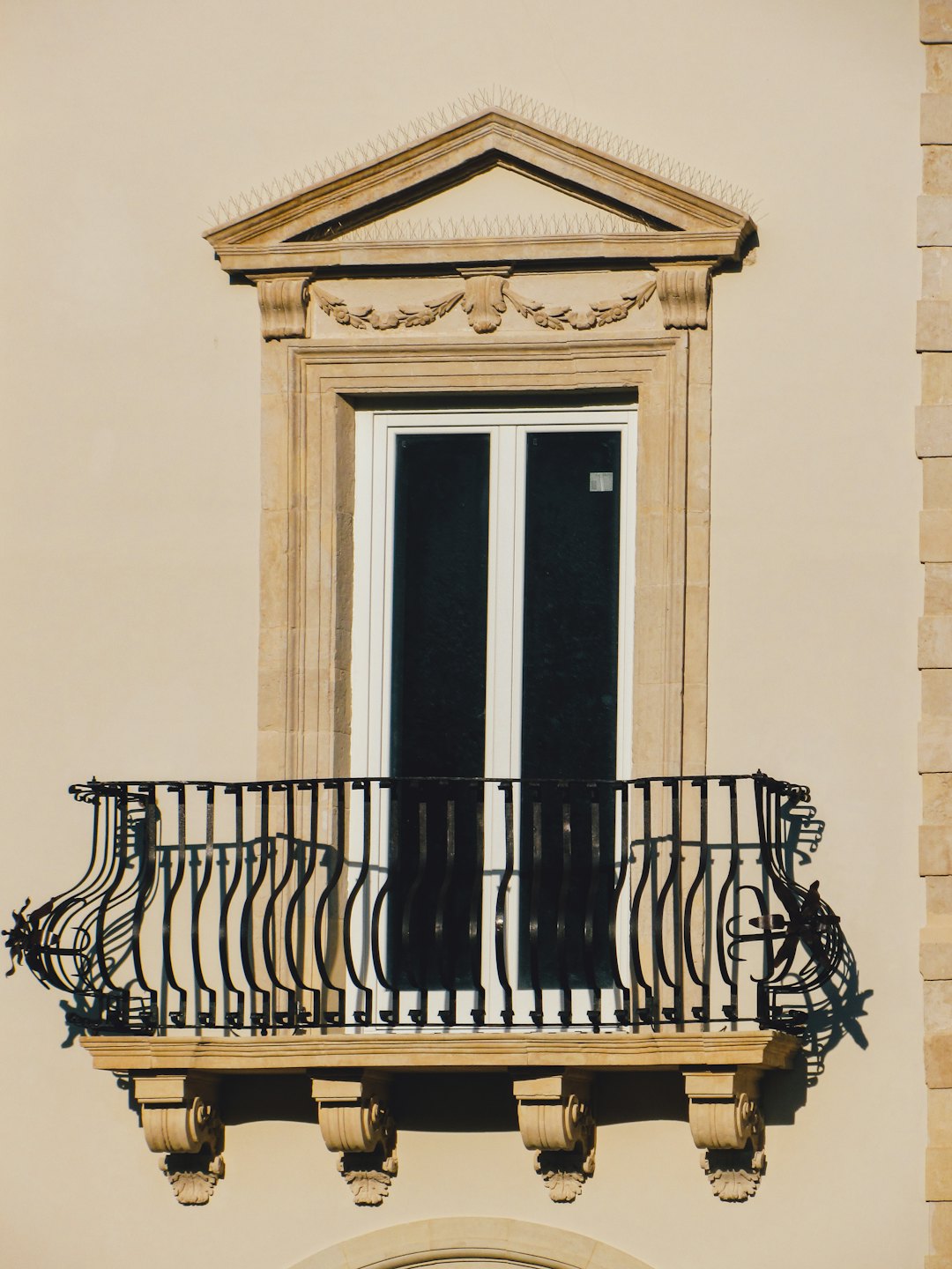 Ornate balcony and window on a stone building with wrought iron railing.