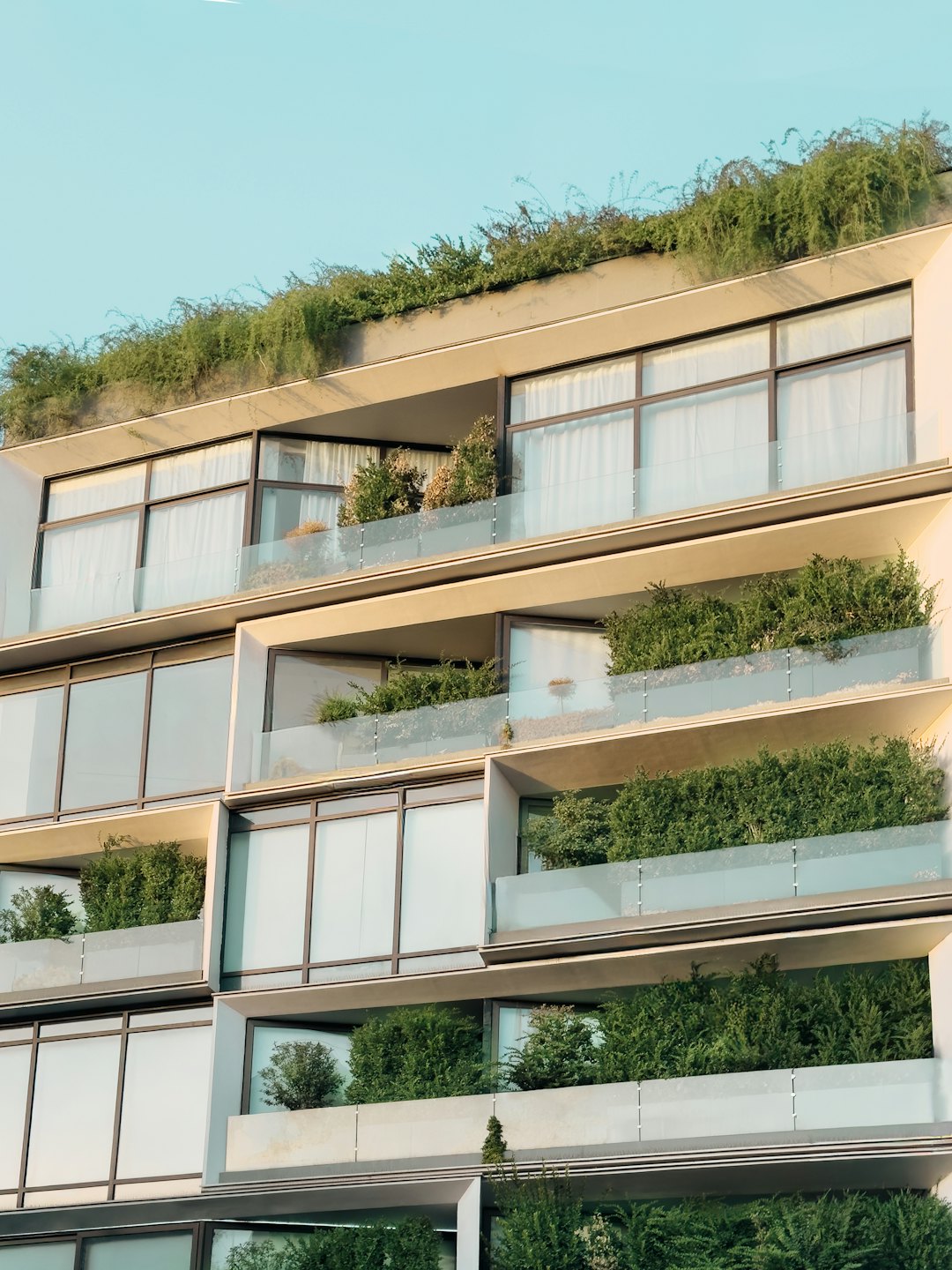 Modern apartment building balconies filled with lush green plants.