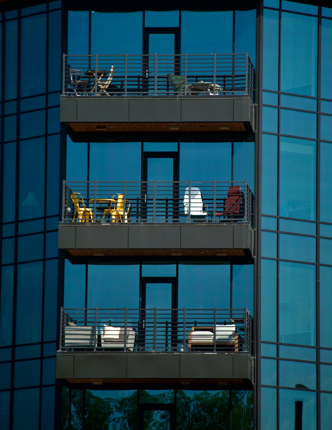 Modern high-rise balconies with yellow chairs and outdoor furniture.