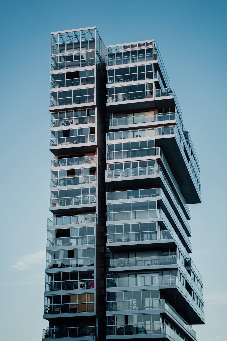 Modern multi-story apartment building with balconies under a clear sky.