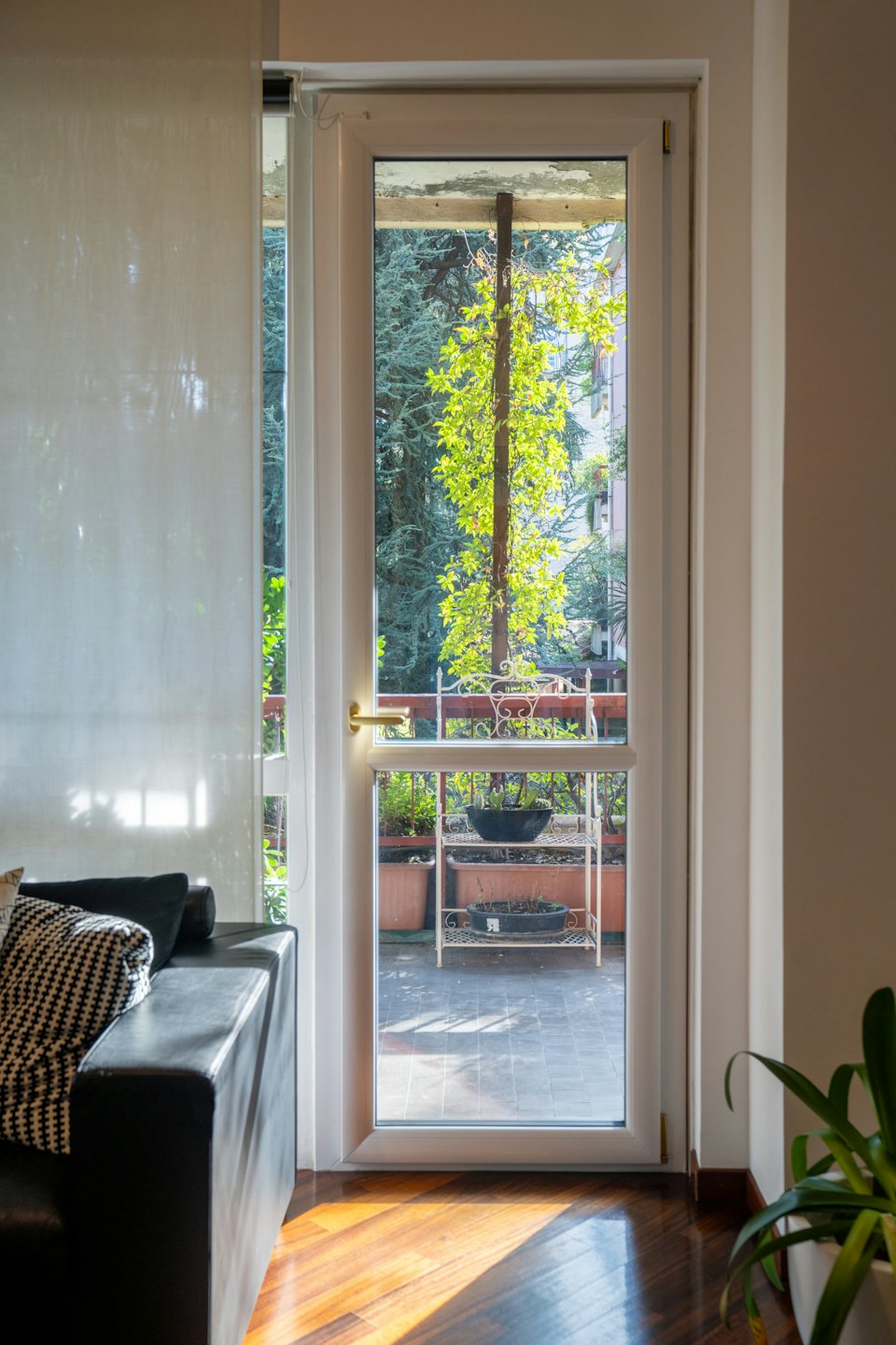 Modern living space looking out onto a sunlit balcony with plants.